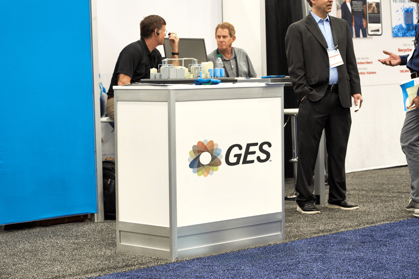 One meter exhibit counter with branding visible on a busy trade show floor